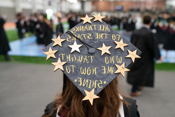 Student wearing graduation cap decorated with gold stars reading All thanks to the stars who taught me how to shine