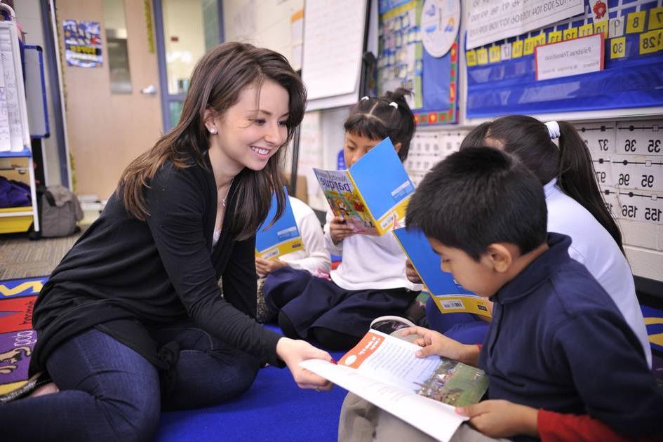 student helping children read in a classroom